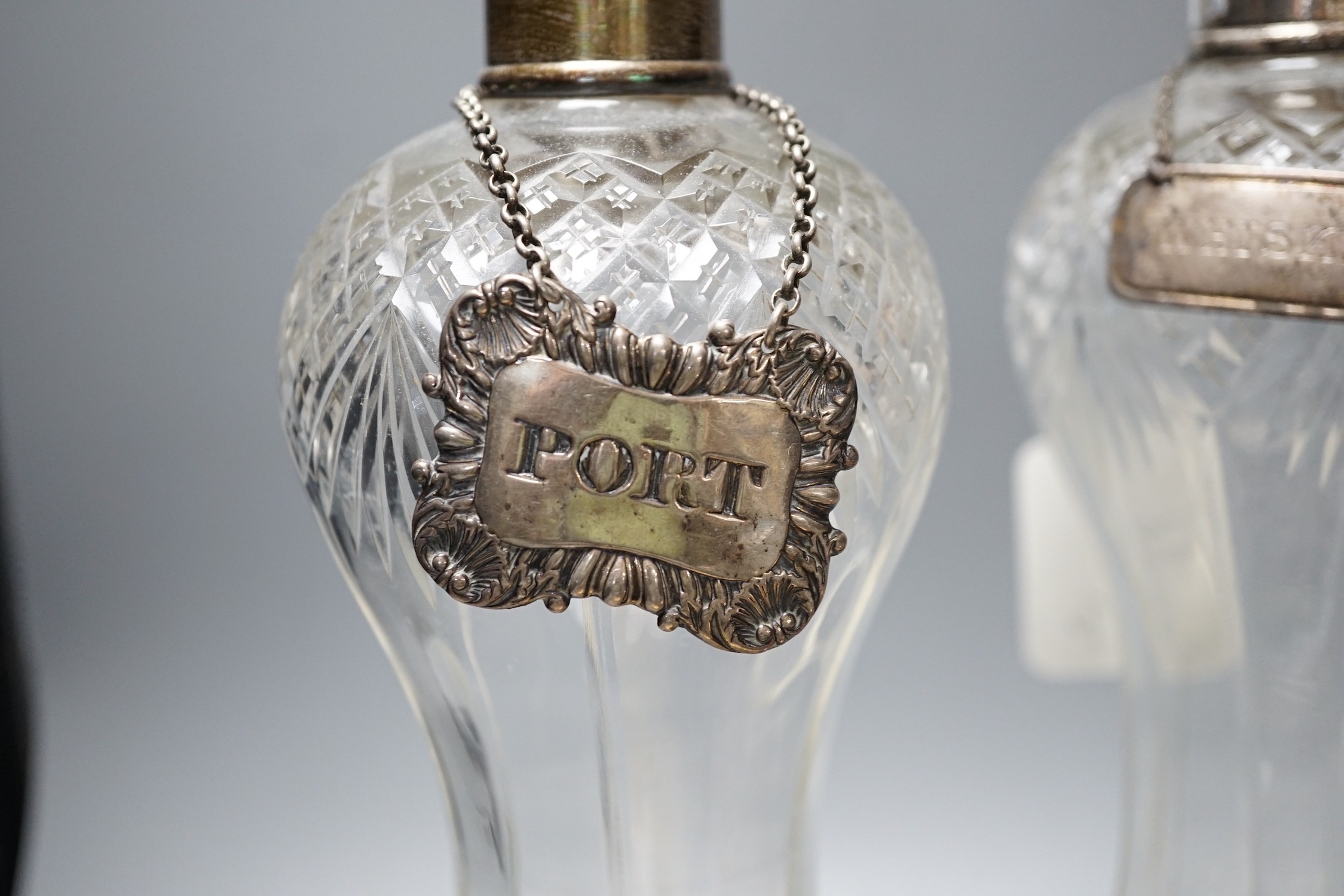 A collection of silver mounted glass items, including a pair of waisted decanters with two silver wine labels, a pair of vases, powder jar etc. and an Indian white metal jar and cover.